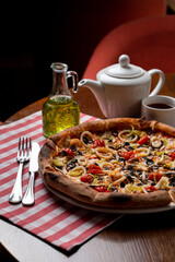 Close up of a lunch in an italian cafe: tomato and cheese pizza on a squared red tablecloth