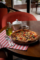 Close up of a lunch in an italian cafe: tomato and cheese pizza on a squared red tablecloth