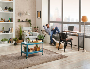 Man in the room, corner interior style, listening to the music with laptop and working from home. Modern decoration style.