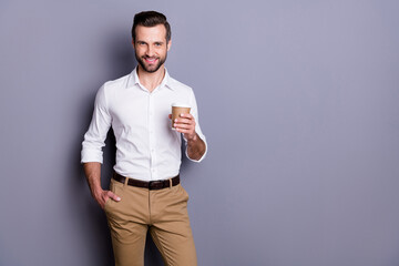 Portrait of positive cheerful man real estate agent economist hold takeaway cup with latte cappuccino enjoy working day rest wear white trousers isolated over gray color background