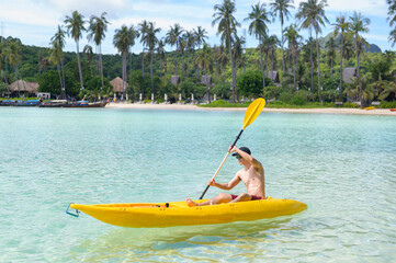 A young sporty man kayaking at the ocean in a sunny day