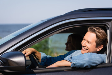 Selective focus of man looking away while driving auto near wife