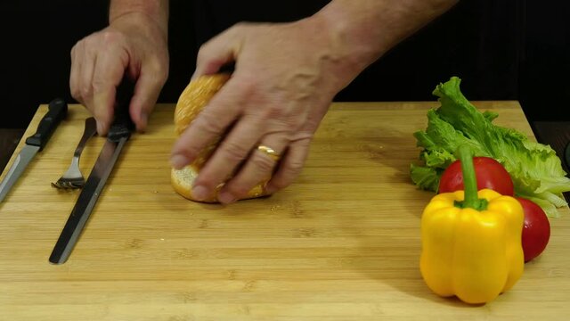 Uomo fa i condimenti del panino con carne, verdure e formaggio
