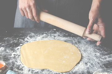 The man's hands prepare the dough for the preparation of pizza and home baking