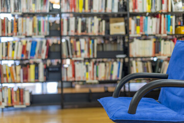 Public library interior with blue armchair and lots of books on the shelves
