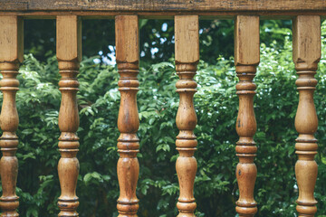 Wooden railing on porch overlooking green garden