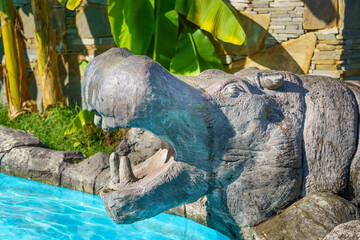Artificially made hippopotamus statuette near the swimming pool. from cement.