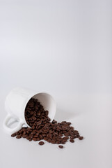 Coffee beans spill out of the cup on white background