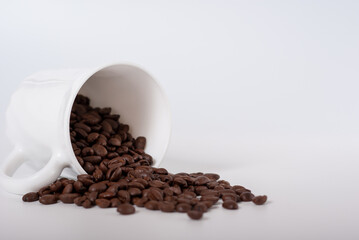 Coffee beans spill out of the cup on white background