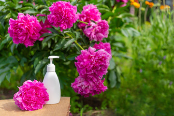 white cosmetic bottle for soap or shampoo on wooden shelf with peonies background. For montage of your product.