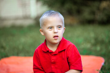 Portrait of a cute little boy with Down syndrome, disabled child laughs and rejoices, caring for...