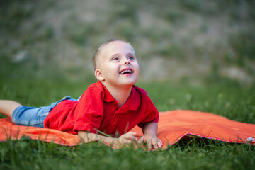 Portrait of a cute little boy with Down syndrome, disabled child laughs and rejoices, caring for...