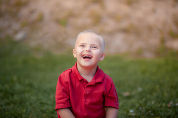 Portrait of a cute little boy with Down syndrome, disabled child laughs and rejoices, caring for...
