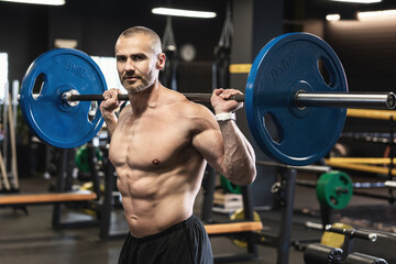 Bodybuilder during his workout with a barbell in the gym