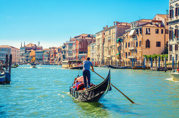 Fototapeta na wymiar Venice cityscape with Grand Canal waterway, Venetian architecture colorful buildings, gondolier on gondola boat sailing Canal Grande, blue sky in sunny summer day. Veneto Region, Northern Italy.