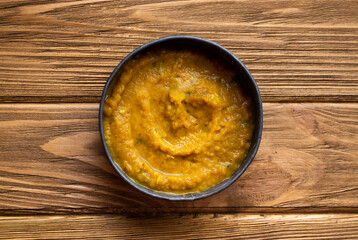 Indian Dal soup on wooden rustic background. Traditional Indian hot soup with chickpeas, vegetables, spices. Healthy vegetarian meal. Top view.