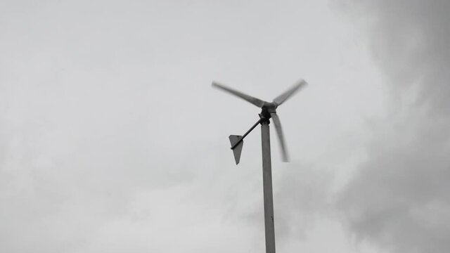 Wind turbines are spinning on cloudy sky background in rainy season. Green energy generation. 