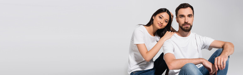 horizontal concept of asian woman leaning on shoulder of boyfriend while sitting on white