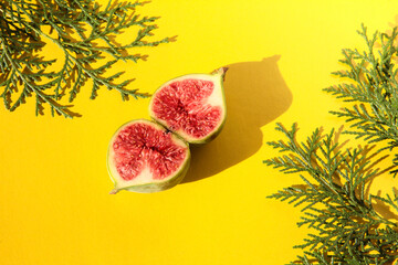 Fig halves on a bright background with thuja branches.