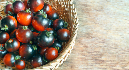 Ripe unusial indigo rose black tomatoes in a basket on a wooden table