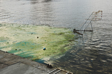 Canoe or water polo stadium. Water pollution with green string algae, plastic rubbish and different...