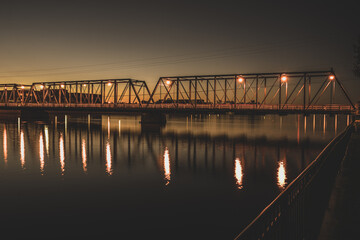 bridge lights reflect on the river at sunset