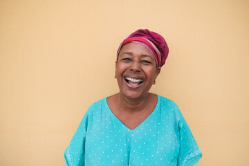 Happy african senior woman laughing and looking in camera - Portrait of real and authentic person wearing traditional dress