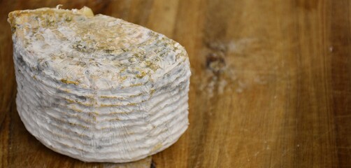 Half goat cheese on wooden board.