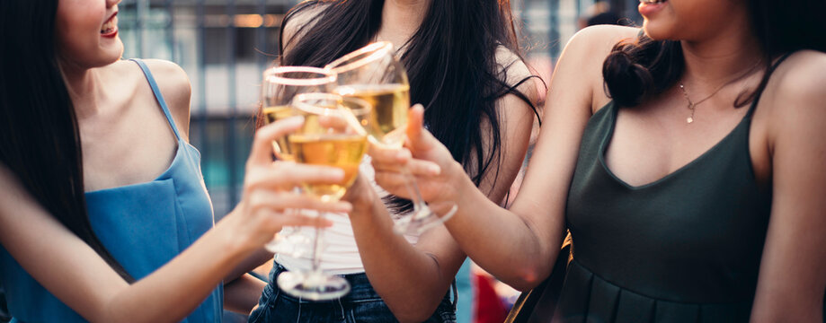 banner group of happy Asian girl friends celebrating party with beer bottle toasting drinks at rooftop cafe in sunset together, female gang chatting, laughing, night lifestyle after self quarantine
