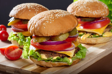 Large Burger with beef Patty on a wooden Board. Burger with tomatoes and pickles. Classic Burger.