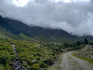 Wanderweg mit Bach und wolkenverhangener Bergkulisse im Sellraintal