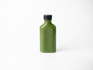 green pastel color drink in plastic bottle container with empty logo label. mixed many vegetables and fruits smoothie juice on studio background.