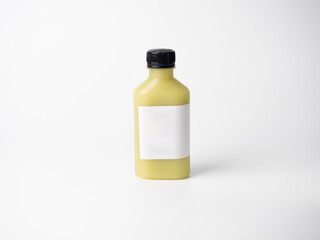 yellow pastel color drink in plastic bottle container with empty logo label. mixed many vegetables and fruits smoothie juice on studio background.
