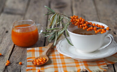 Sea buckthorn branches with berries, tea, honey and sea buckthorn jam on a wooden background. The...