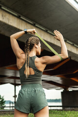 Athletic woman during workout with a resistance rubber band on a street