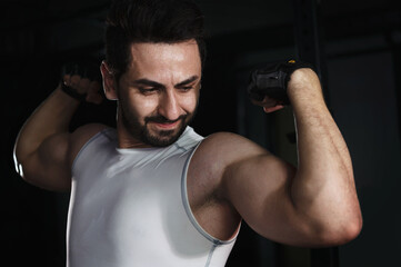 Fototapeta na wymiar Fit muscular male bodybuilder posts two arm bicep curl in gym fitness