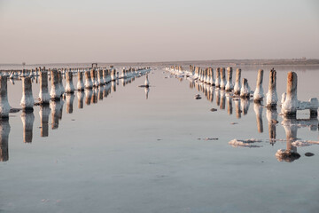 Unique salt lake Kuyalnik in Ukraine. Wooden poles reflected on the surface with the salt crystals. 