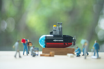 Miniature worker people with toy submarine