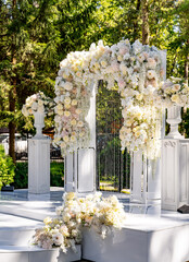 Wedding arch in the garden. White arch decorated with tender light flowers.