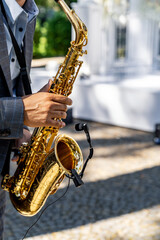 Obraz premium Young man playing the saxophone at the wedding. Blurred background. Selective focus.