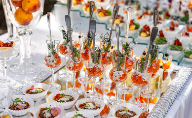 Appetizers in little glasses on white table blurred background. Party table. Catering concept.