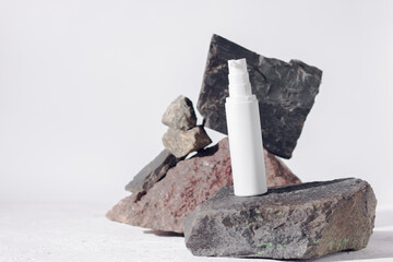 Unbranded medical skincare products white plastic bottle with dispenser and flacons. Tube for cream or shampoo. White background isolated, concrete stones and granite rocks