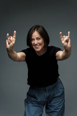 Middle aged woman wearing black t-shirt showing sign of the horns