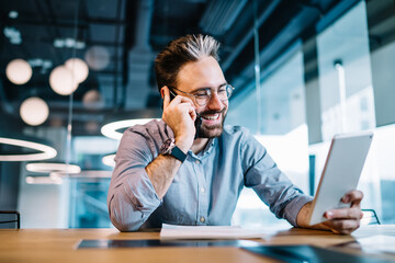 Happy businessman with tablet talking on phone