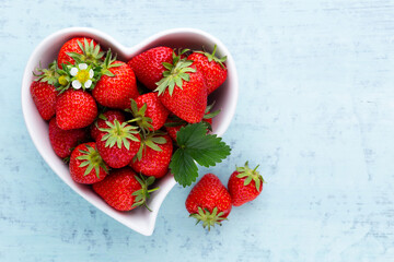 Strawberry heart. Fresh strawberries in plate on white wooden table. Top view, copy space.