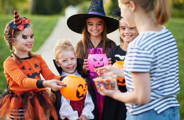 Woman giving treats to children in costumes.