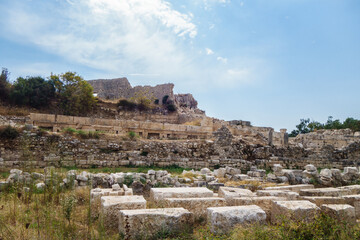 Fototapeta na wymiar Remains of walls surrounding Byzantine palace in ancient city Elaiussa Sebaste, near Kızkalesi, Turkey. Ruins of palace itself are on hill (background). City was abandoned in medieval