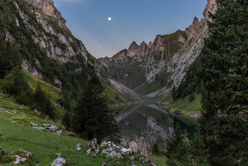The moon and the Alpstein mountain range reflecting on the Faelensee lake in the Swiss canton of...