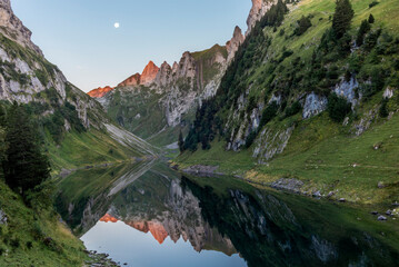The moon and the Alpstein mountain range reflecting on the Faelensee lake in the Swiss canton of...