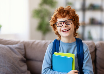 Excited schoolboy with textbooks smiling.